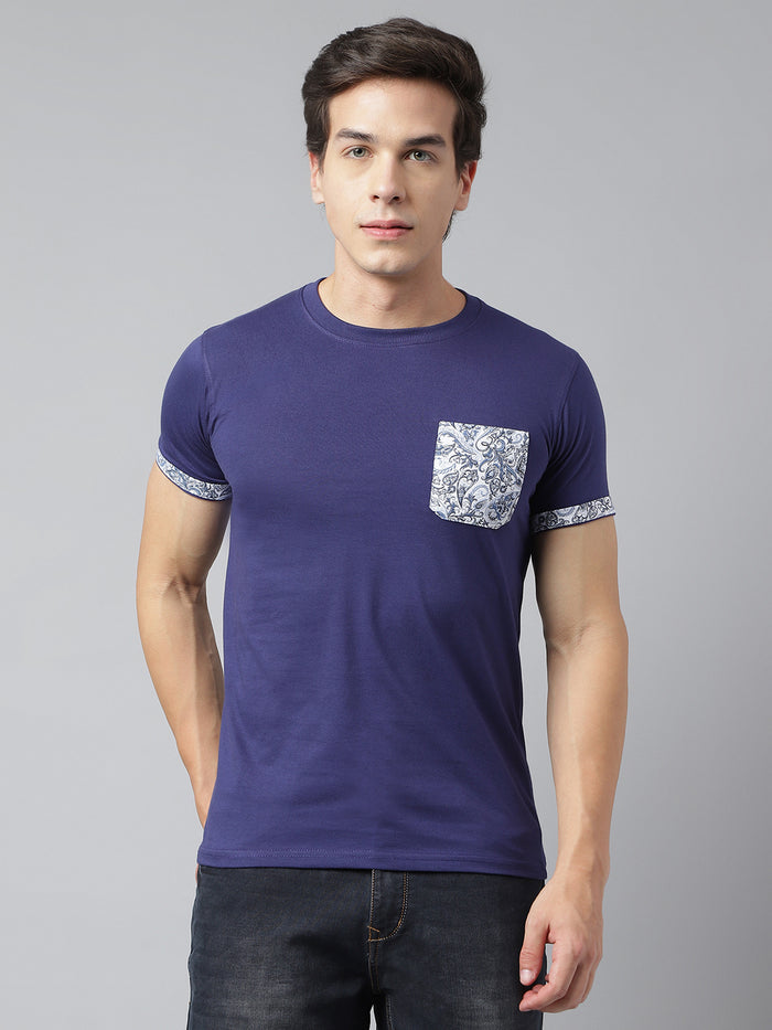 A man wearing a blue round neck T-shirt with a solid pattern and a pocket on the chest.