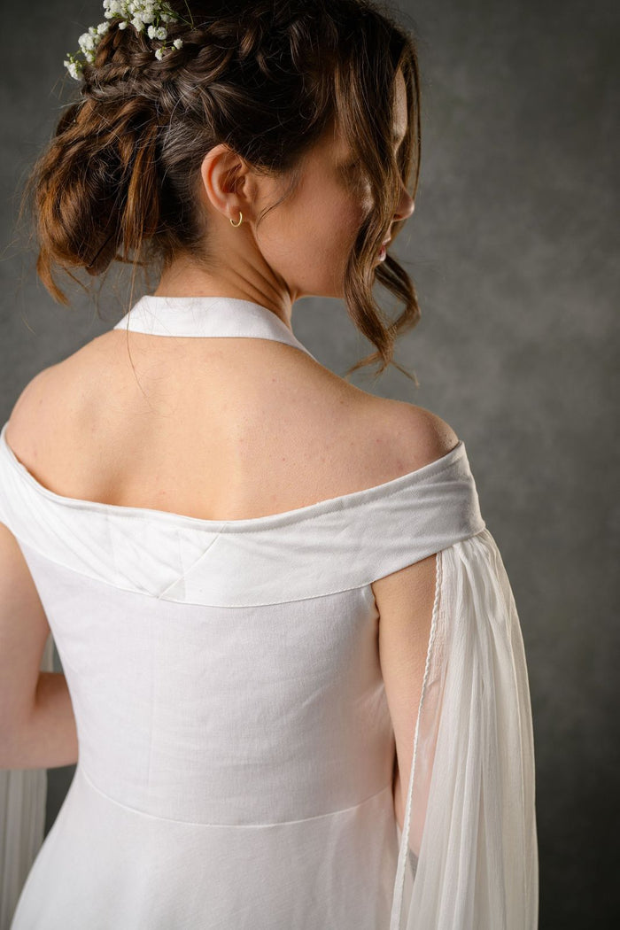 Close-up of ivory wedding dress back with off shoulder detail, halter neckline and chiffon draped sleeve