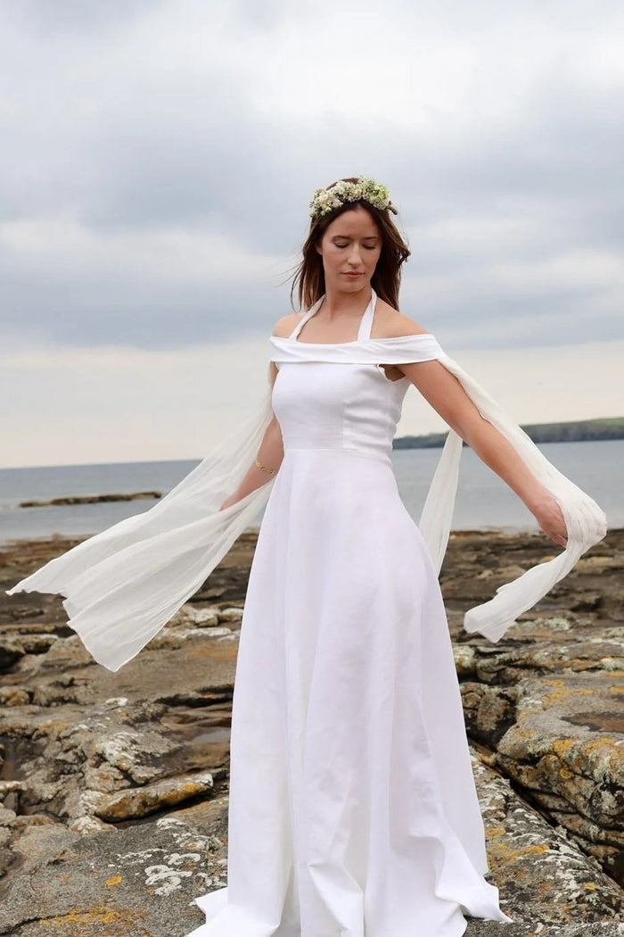 Simple ivory fairytale wedding dress with flowing drape sleeves styled for a coastal bridal look