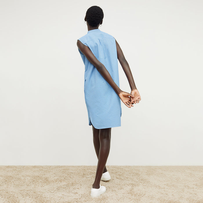 Back image of a woman standing wearing the gigi dress in gingham seersucker in capri blue and white