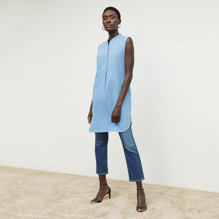 Front image of a woman standing wearing the gigi dress in gingham seersucker in capri blue and white
