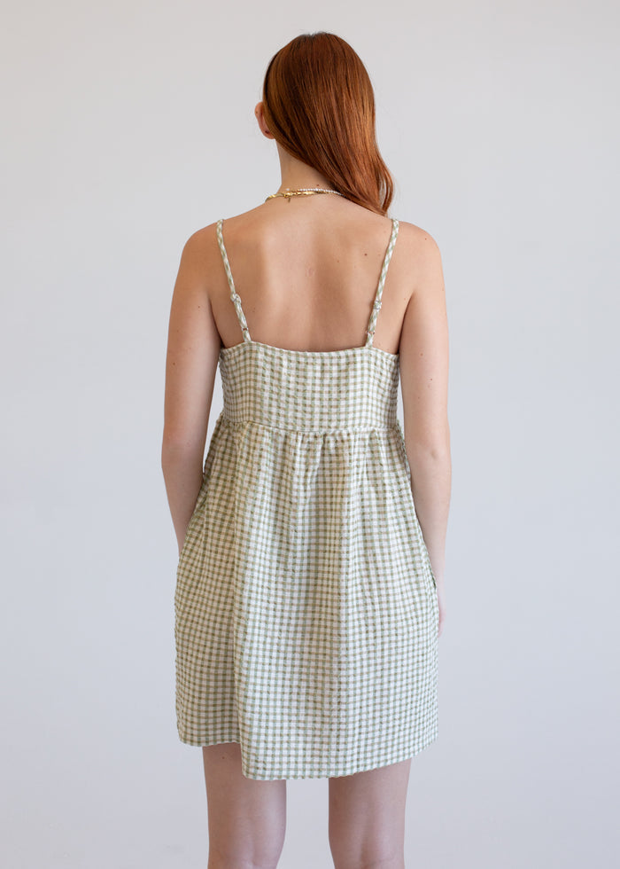 Woman wearing a green checkered dress against a plain background