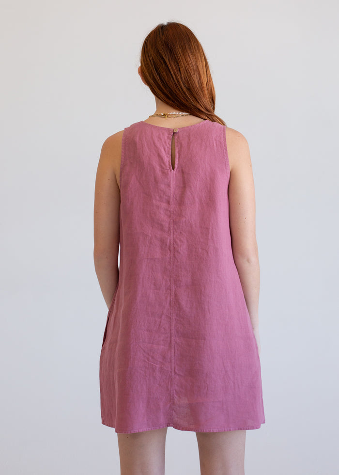 Woman wearing a pink sleeveless dress against a plain background