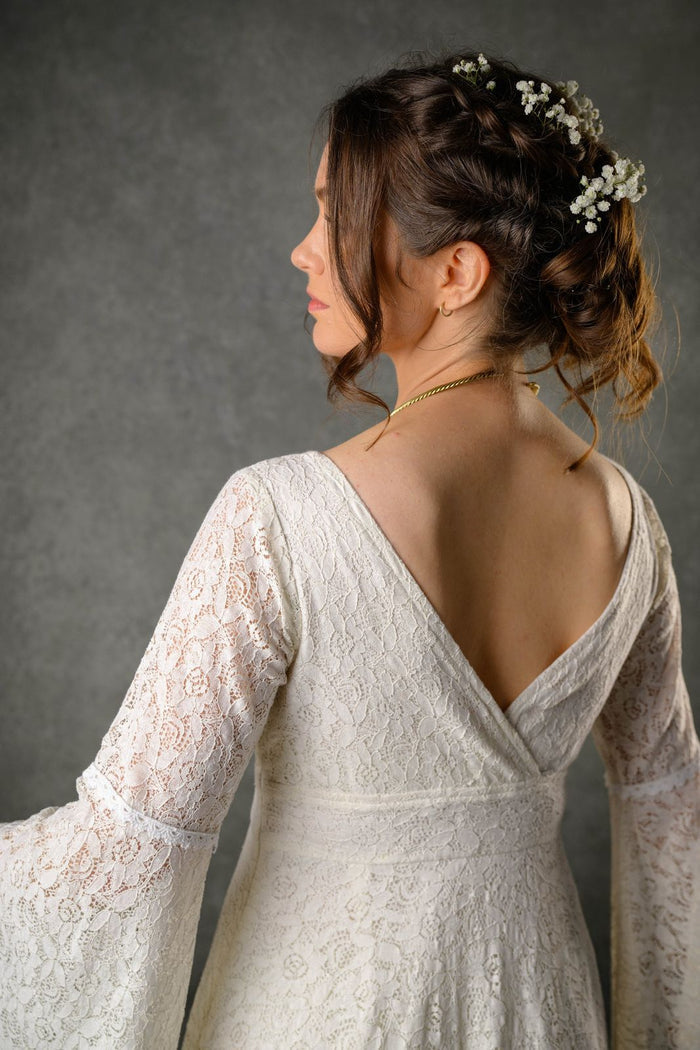 Ivory cotton lace bridal gown from the back with low V neckline, floral lace and flowing sleeves