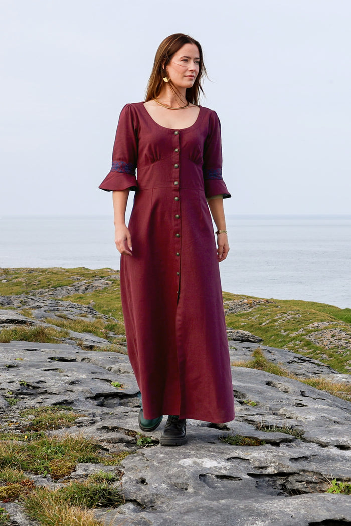Front view of button front burgundy folklore dress with elegant long silhouette, flared sleeves with celtic embroidery and Irish-inspired styling by Celtic Fusion
