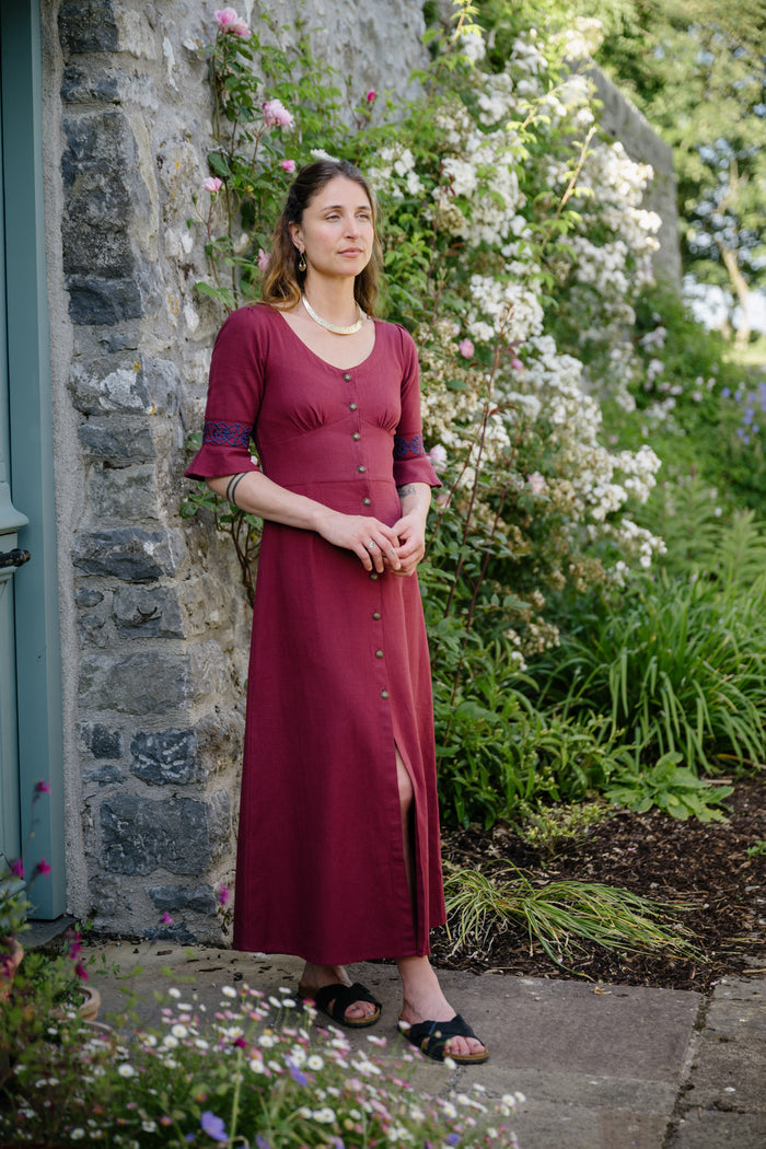 Classy subtle celtic dress in burgundy berry red tones photographed in a flower garden in Ireland
