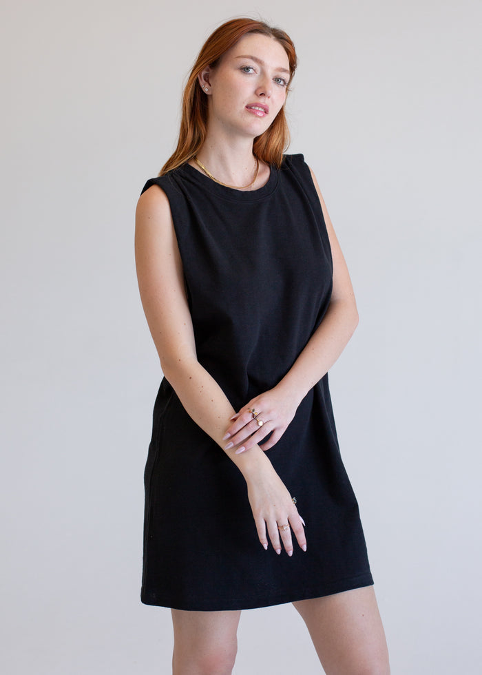Woman wearing a boxy tank dress against a plain background