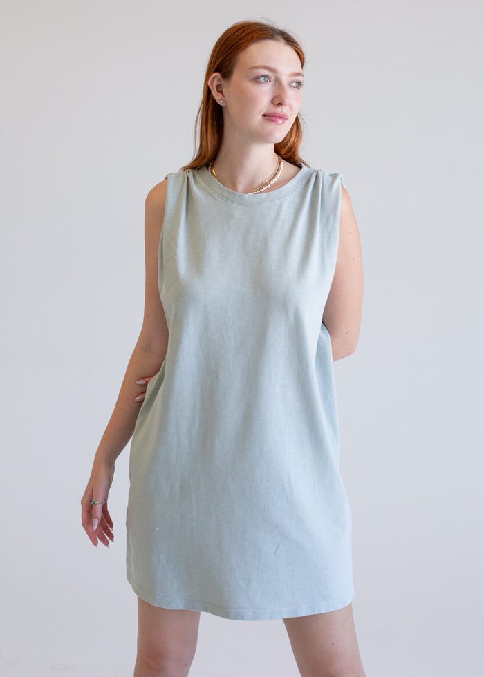 Woman wearing a sage boxy tank dress against a plain background