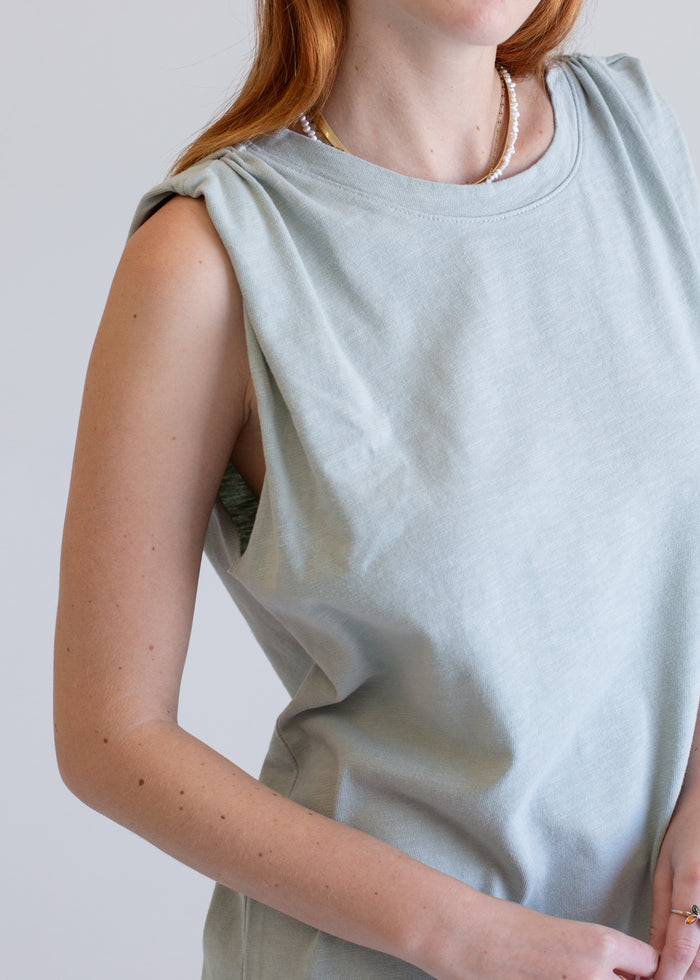 Person wearing a light green boxy tank dress against a plain background