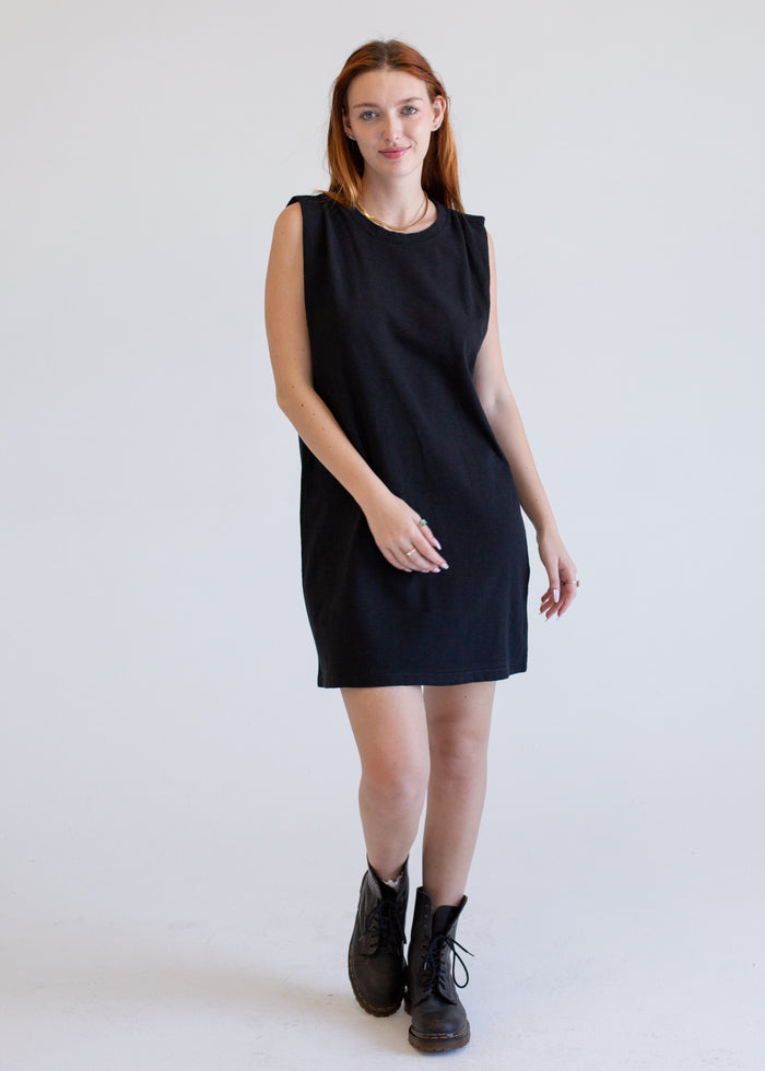 Woman wearing a black boxy tank dress against a white background