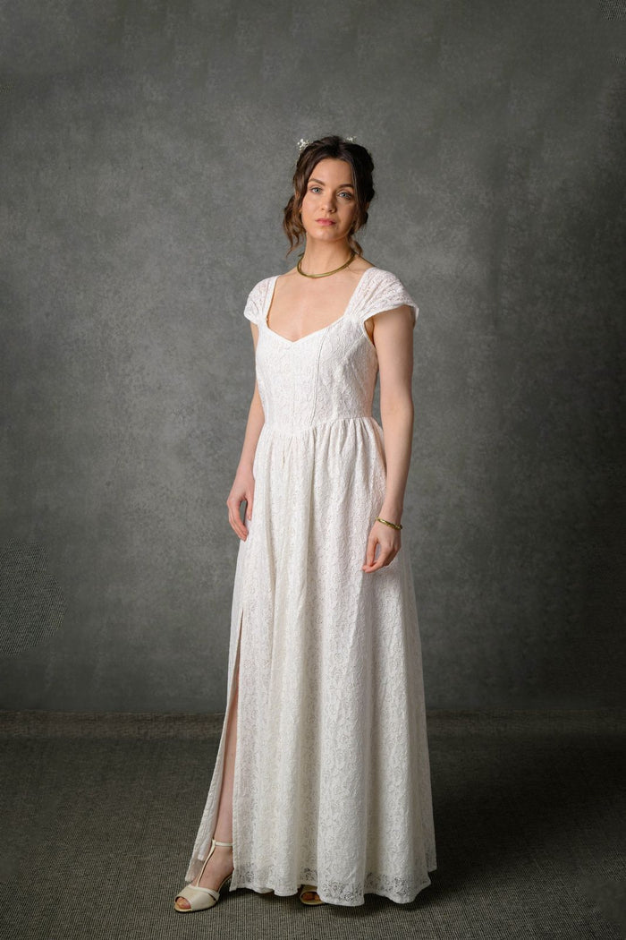 Natural bridal gown in ivory floral cotton lace with corset-style bodice and elegant flowing full-length skirt